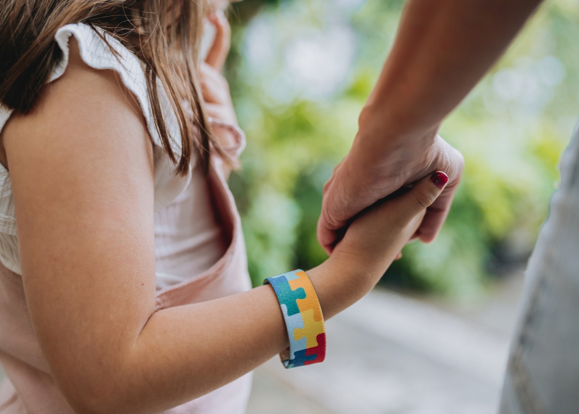 Autistic child holding hands with his mother