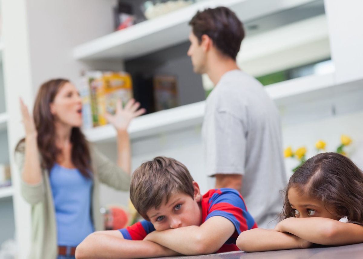 Couple arguing behind their children in the kitchen