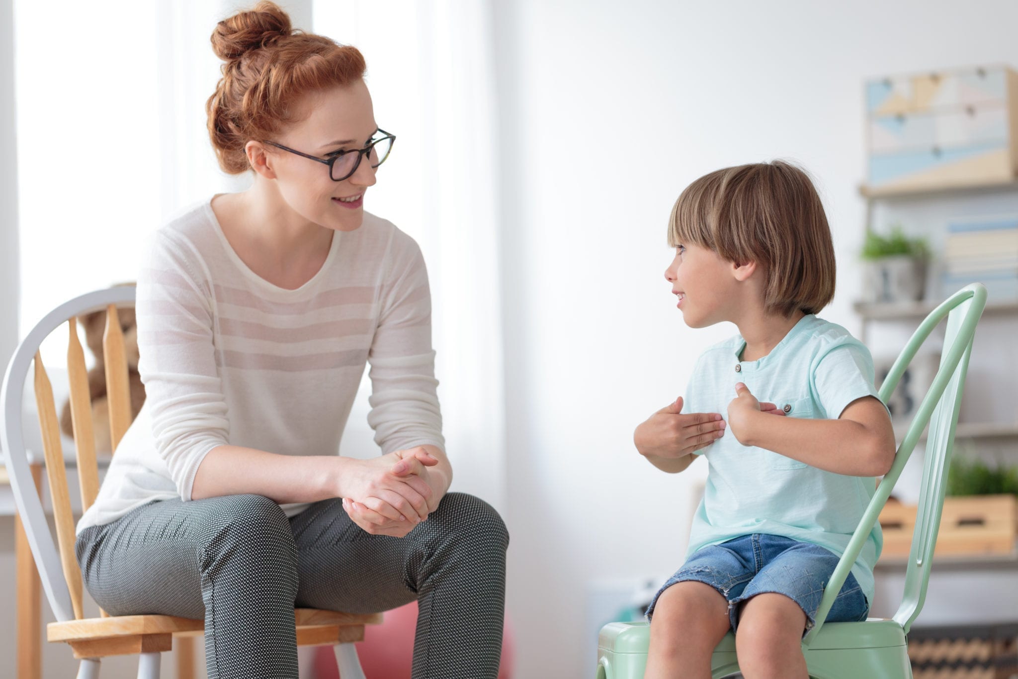 Image of a woman sitting down speaking to a young boy.