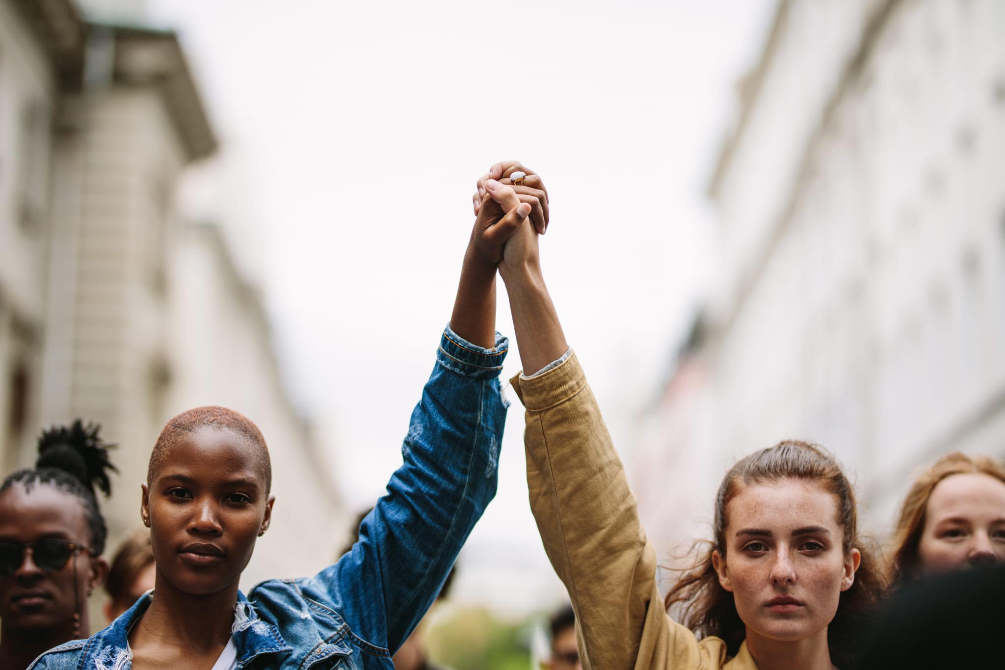 Image of a black woman holding hands with a white woman with their arms raised in the air.