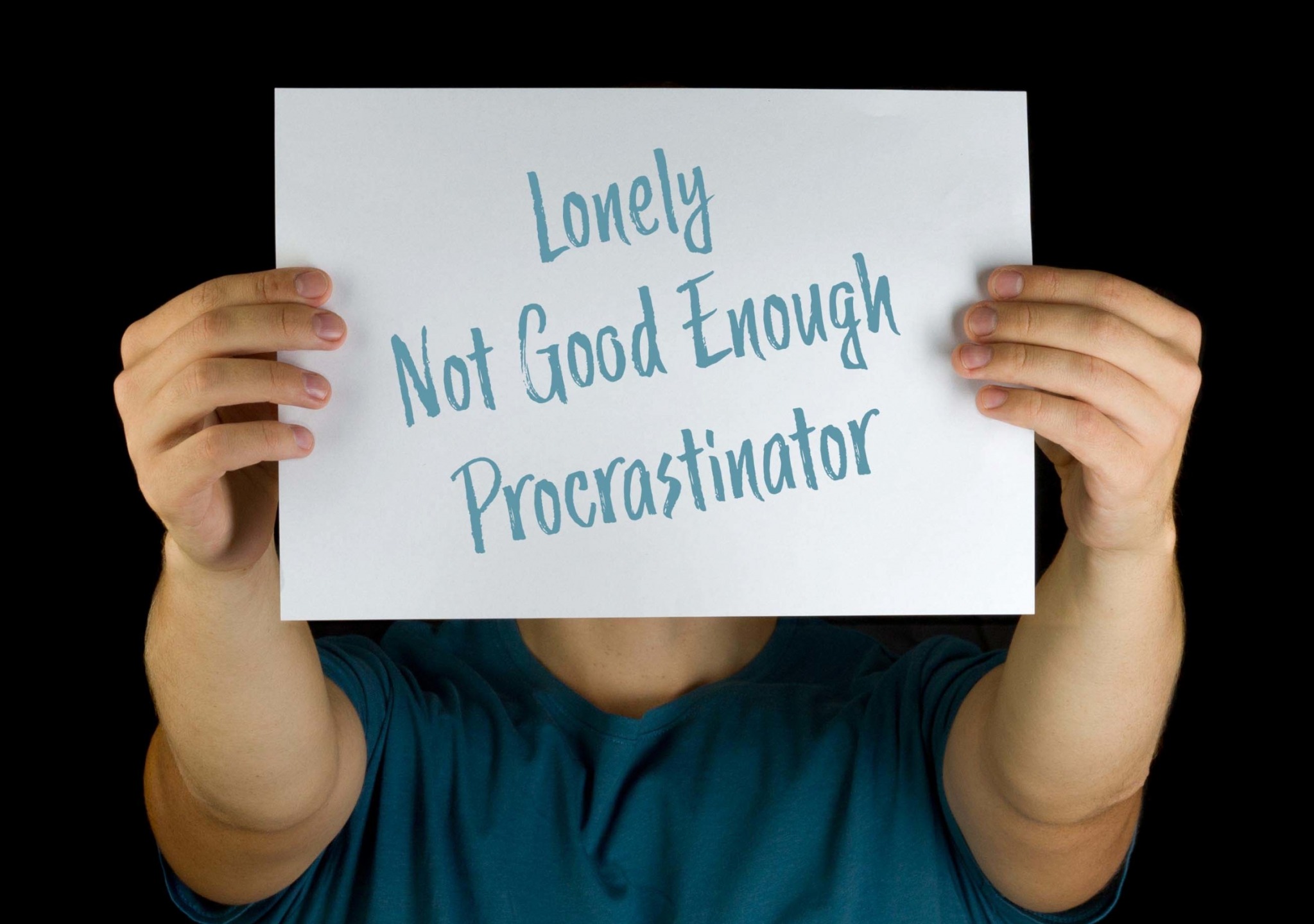 Stock Photo of a Held Out Poster Reading "Lonely / Not Good Enough / Procrastinator