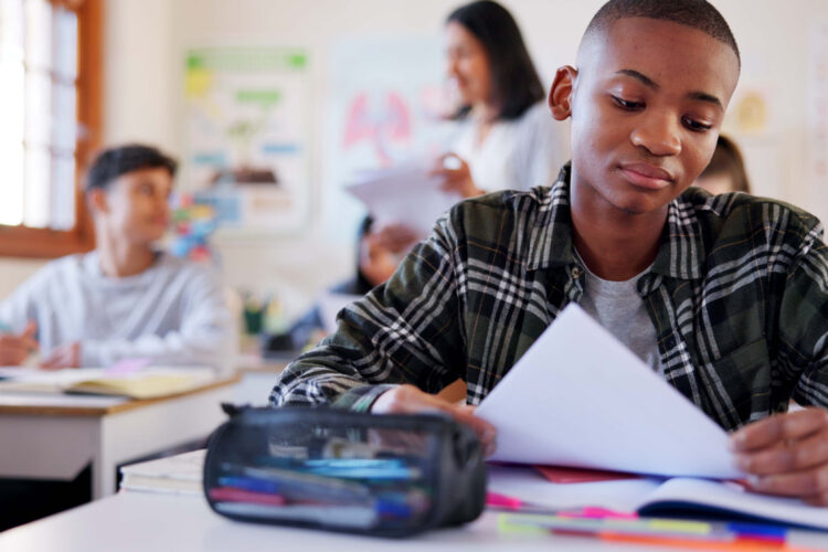 Sad child, student or test with stress for bad result, feedback or exam in classroom at school. Young, kid or disappointed teenager with paper or document for mistake, failure or academic examination